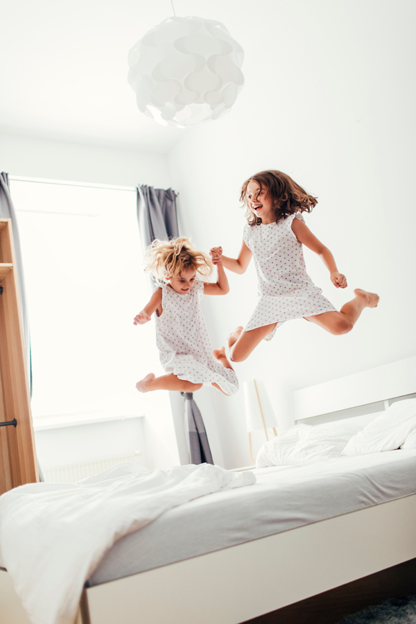 Deux petites filles s'amusent en sautant sur un grand lit